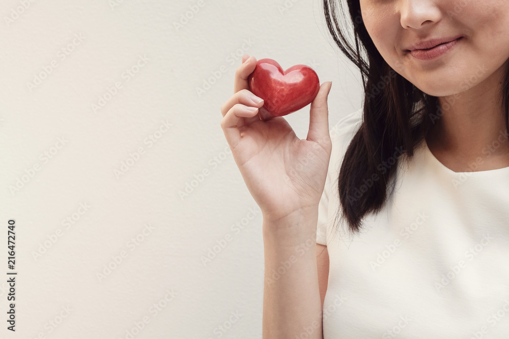 Asian young woman holding red heart, health insurance, donation, charity, CSR concept, stop Asian hate Asian young woman holding red heart, health insurance, donation, charity, CSR concept, stop Asian hate