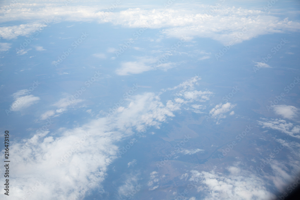 Fototapeta premium Clouds and sky as seen through window of an aircraft