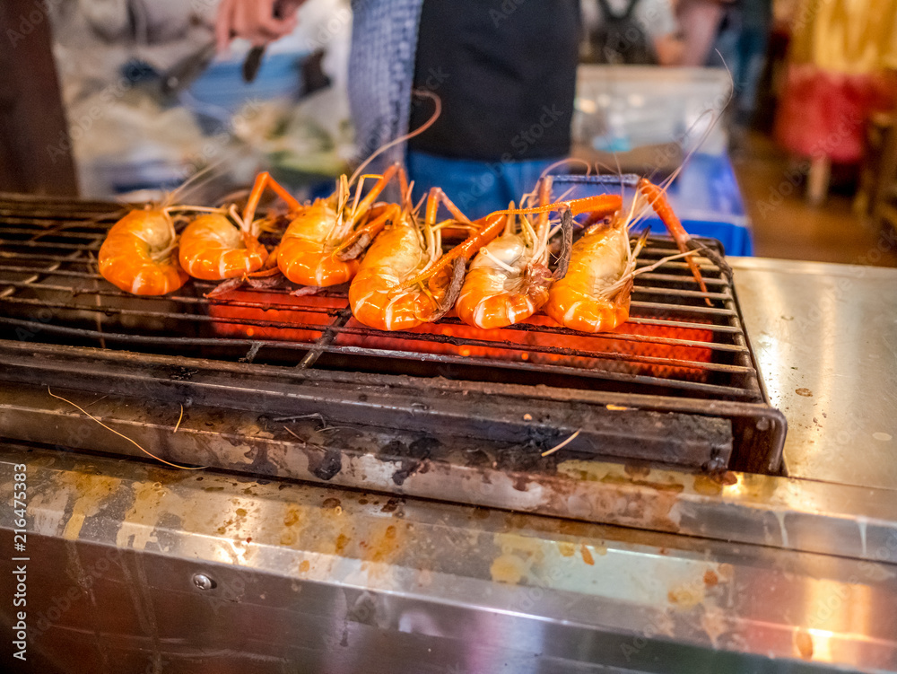 Grilled giant river prawn or big shrimp on stove with selective focus.A recommended menu for tourists when they come to Thailand. The prawn is served with spicy seafood sauce.