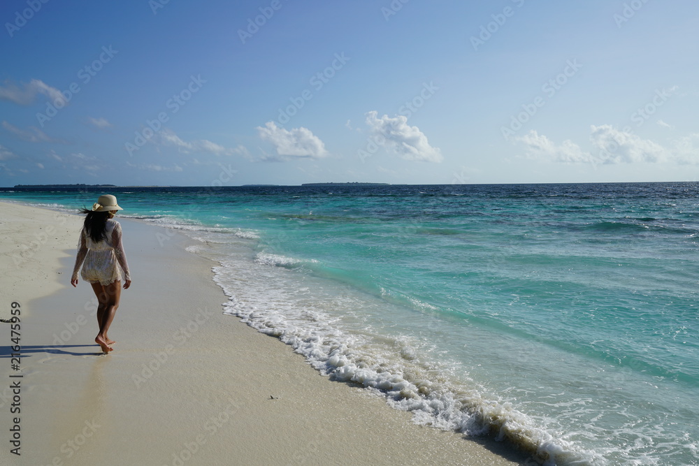Young woman walking along the beach in the Maldives