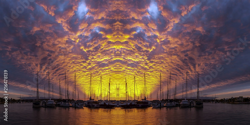 Photos Orange colored altocumulus cloud, sunset seascape over marina.