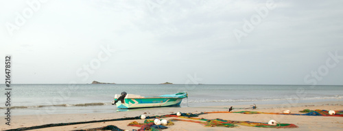 Fototapeta Naklejka Na Ścianę i Meble -  Small fishing boat next to fishing nets drying on Nilaveli beach in Trincomalee Sri Lanka Asia