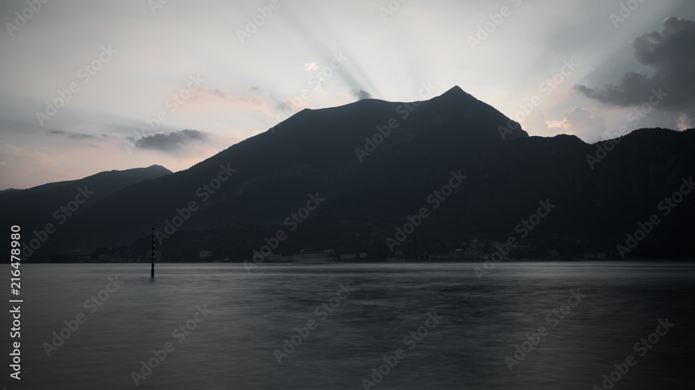 mountains alps and lake como with sun shine and cloudy sky at sunset
