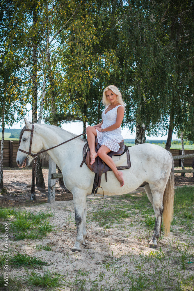Pretty girl lady at countryside with white horse. A beautiful rider and horse. Artistic Photography at horse farm. Attractive girl riding on horse rural location 