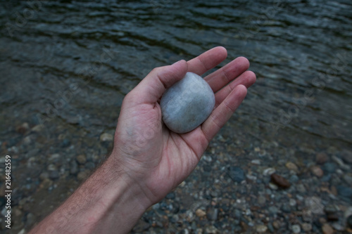 Pebble lying on palm against the water