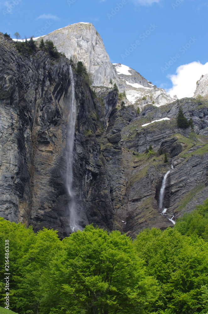 Une cascade en montagne dans les Alpes en France avec des arbres et de la neige