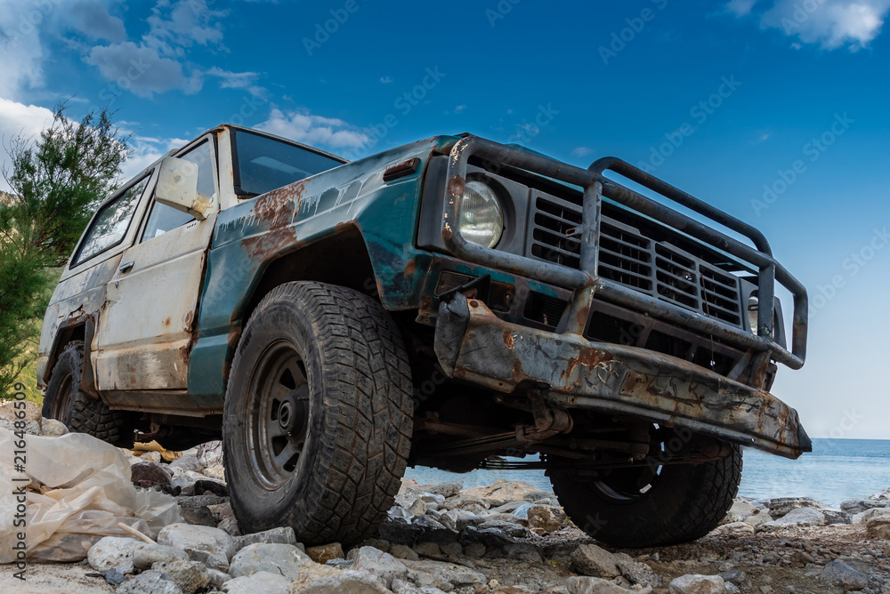 Fototapeta premium Stary, wytrzymały pojazd terenowy utknął w skalistym terenie