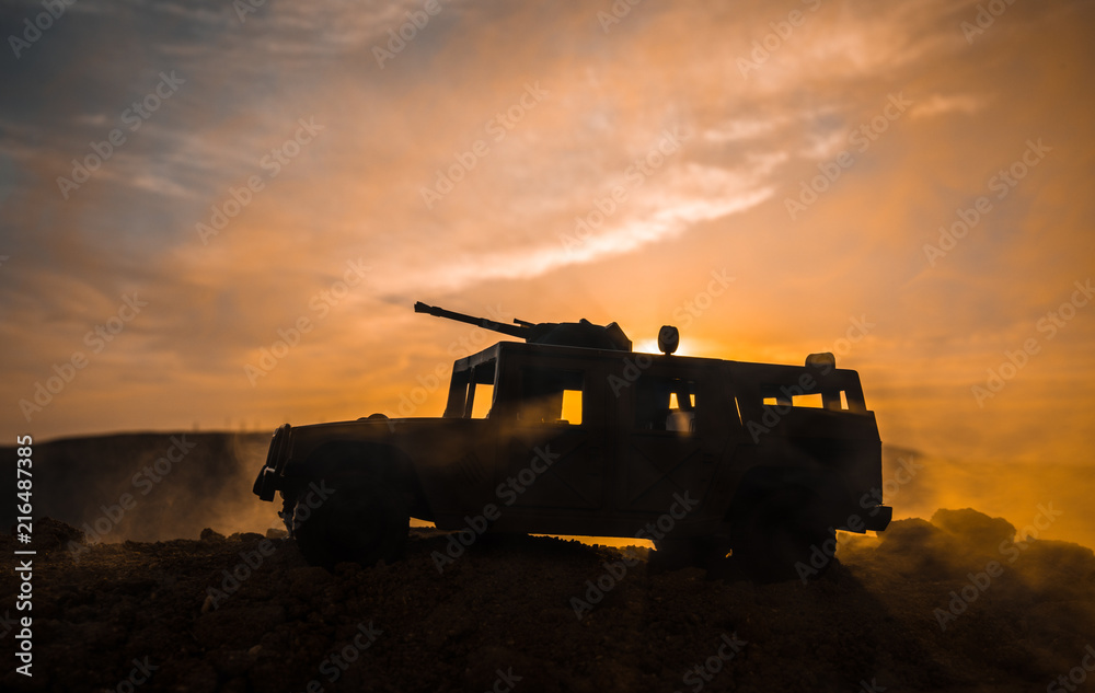 Military patrol car on sunset background. Army war concept. Silhouette of armored vehicle with gun in action. Decorated.