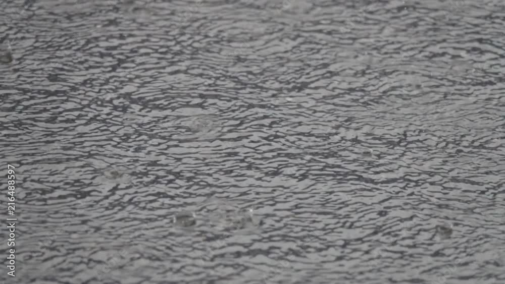 Rain drops rippling in a puddle with blue sky reflection. Rain create interesting ripples and circles in pond. Rain drops rippling in a puddle with blue sky reflection. Rain create interesting ripples and circles in pond.