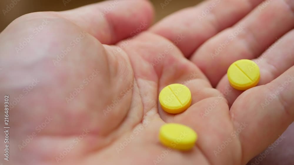 Person pouring bunch of prescription yellow opiate pills into hand Person pouring bunch of prescription yellow opiate pills into hand