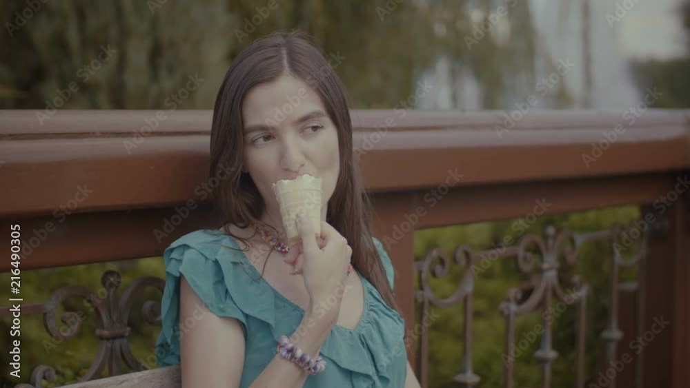 Portrait of joyful beautiful long brown hair woman with eyes closed eating tasty refreshing ice cream while sitting on the bench on hot summer day during vacation. Portrait of joyful beautiful long brown hair woman with eyes closed eating tasty refreshing ice cream while sitting on the bench on hot summer day during vacation.