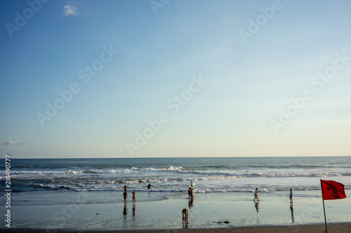 people on ocean beach with waves and warning flag