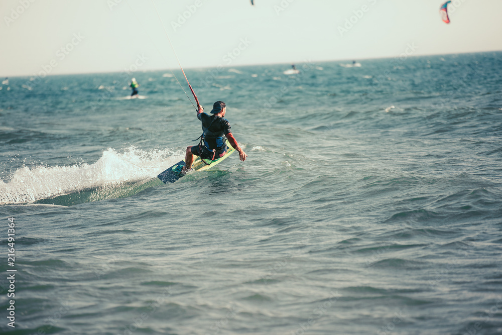 Professional kiter makes the difficult trick on a beautiful background. Kitesurfing Kiteboarding action photos man among waves quickly goes Professional kiter makes the difficult trick on a beautiful background. Kitesurfing Kiteboarding action photos man among waves quickly goes