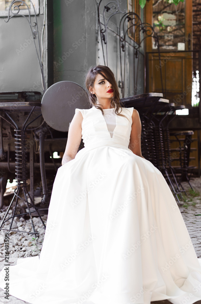 Naklejka premium Girl sitting next to old train in white dress