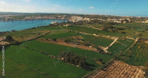 Aerial Shot - Flying backwards over green lands and blue sea
