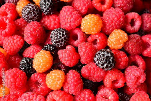 Berry mix  red raspberry  yellow raspberry and blackberry.Background of different berries. Colors  red  yellow and black. Ripe juicy berries. Macro. Closeup.