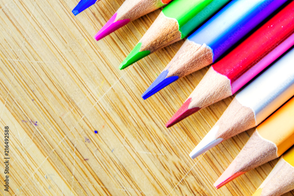 Obraz premium multicolored pencils on wooden background forming a pattern with copy space