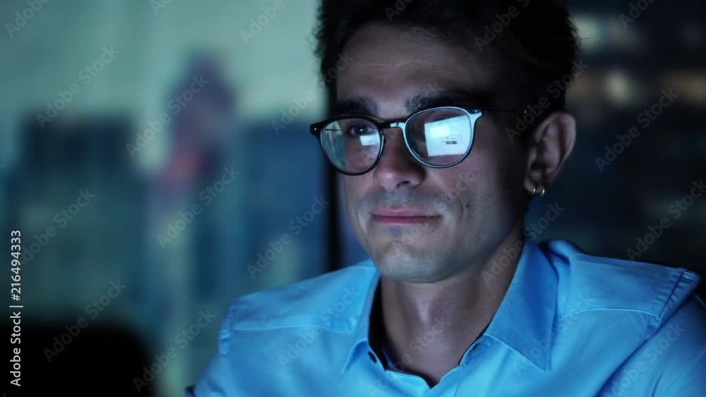Portrait of Handsome Young Businessman Working in the Office At Night. Broker Using Laptop, Looking at The Monitor