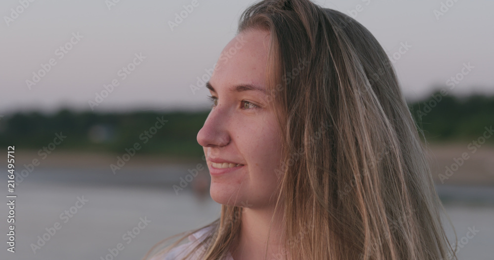 teenage girl standing on a beach at sunset