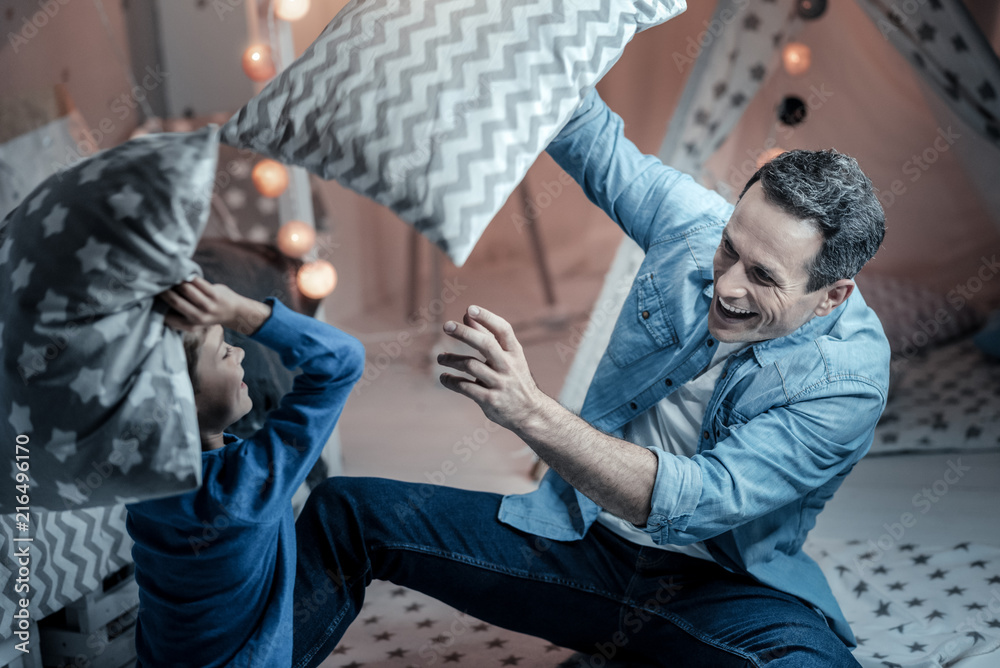 Fototapeta premium Lets play. Happy male person laughing while playing with his son