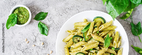 Penne pasta with  pesto sauce, zucchini, green peas and basil. Italian food. Top view. Flat lay. Banner