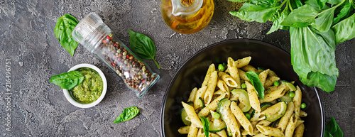 Penne pasta with  pesto sauce, zucchini, green peas and basil. Italian food. Top view. Flat lay. Banner