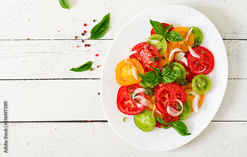 Colored tomato salad with onion and basil pesto. Vegan food. Top view. Flat lay