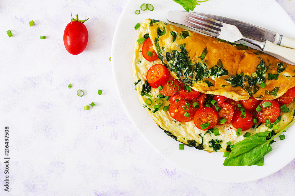 Omelette with tomatoes, spinach and green onion on white plate. Frittata - italian omelet. Top view. Flat lay. Omelette with tomatoes, spinach and green onion on white plate. Frittata - italian omelet. Top view. Flat lay.