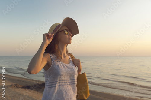 Young and beautiful woman wearing a hat in sunset light looking far away at horizon