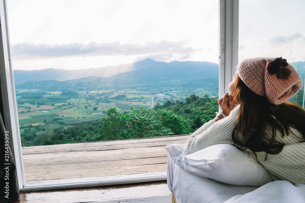 Young women sat on a wooden floor and enjoy  mountain view in the morning.