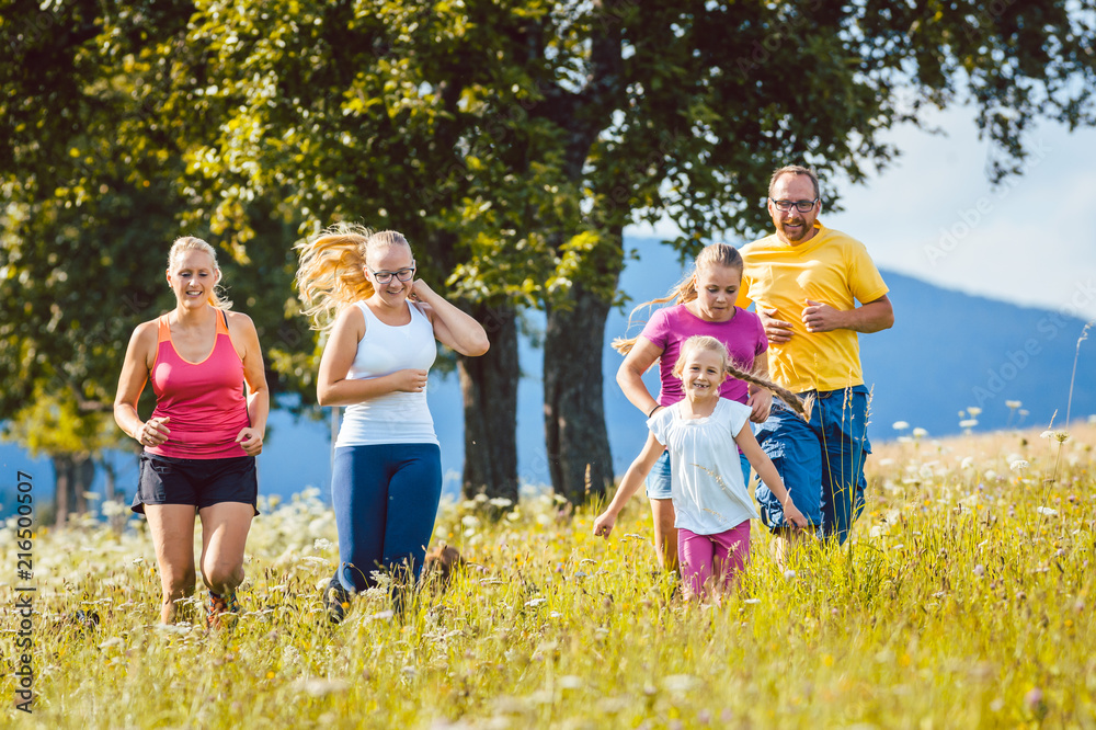 Obraz premium Family, mother, father and kids running for sport over a meadow