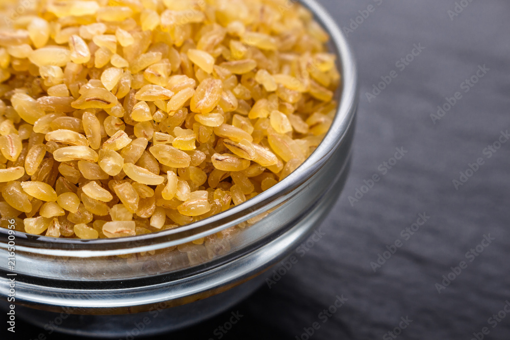 raw bulgur on a dark stone background raw bulgur on a dark stone background