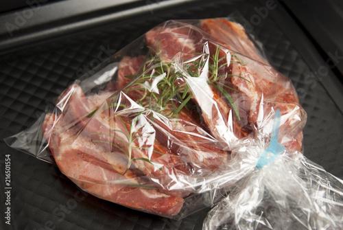 Cooking baking plastic bag. No pastic concept. Fresh pork meat steake packaged in a sleeve with spices, for baking is ready for baking, isolated on black background. Top view. photo