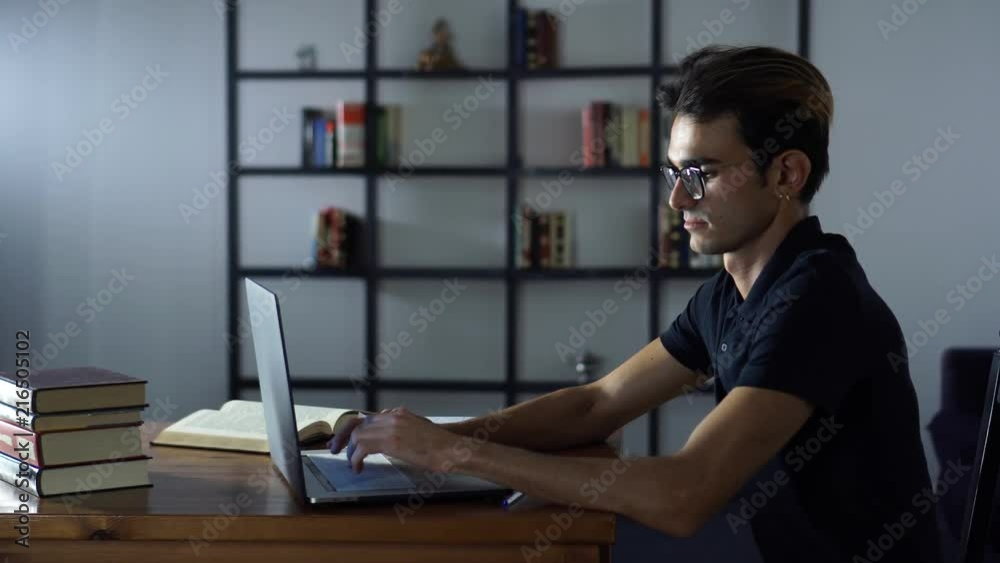 Attractive Serious Student Studying with Computer, Typing Notes, Looking at the Laptop Attractive Serious Student Studying with Computer, Typing Notes, Looking at the Laptop