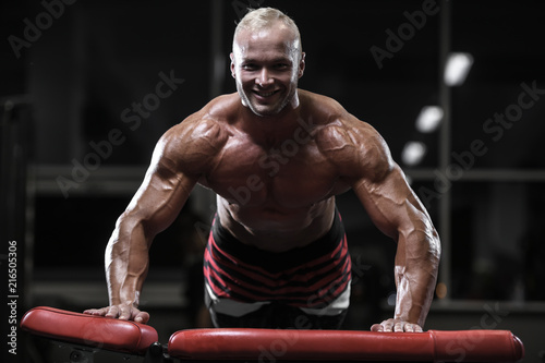 Handsome strong bodybuilder athletic men pumping up muscles with dumbbells