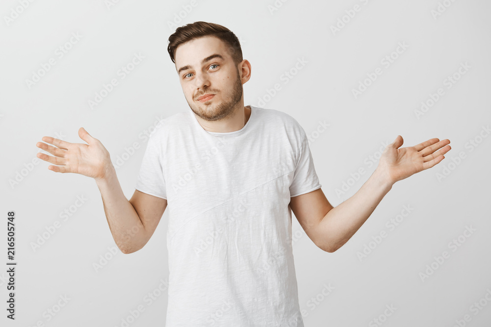 I have no idea man ask anyone else. Careless relaxed handsome unshaven guy with stylish haircut in white t-shirt making shoulder shrug gesture with palms spread aside being clueless and unaware I have no idea man ask anyone else. Careless relaxed handsome unshaven guy with stylish haircut in white t-shirt making shoulder shrug gesture with palms spread aside being clueless and unaware