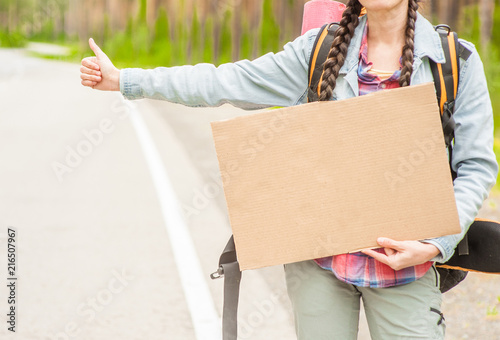 Close up girl travels hitchhiking with a cardboard sign in her hands. Space for text