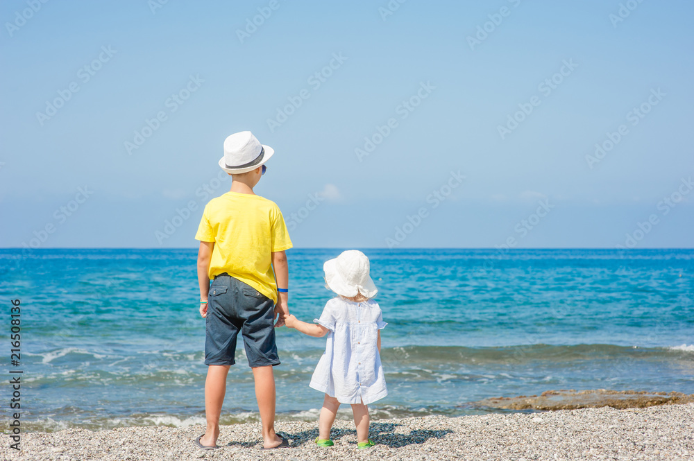 Boy and girl standing holding hands on the beach on summer holidays. concept of summer family vacation. Space for text