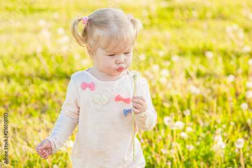 Funny baby girl blowing a dandelion