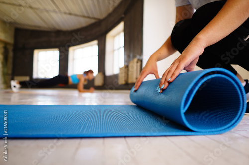 Active lifestyle, yoga trainer, flexibility, sport, fitness. Hands of young woman rolling yoga mat before class in studio