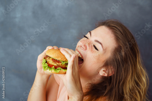 Pleasure  delight  enjoyment  treat  happiness  appetite  fast food  hunger. Cute young woman eating delicious burger enjoying the taste