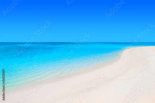 Lonely sandy beach with turquoise ocean and blue sky