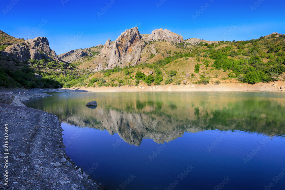 A beautiful mountain lake, where the mountains are reflected in the water in Zelenogorye, Crimea A beautiful mountain lake, where the mountains are reflected in the water in Zelenogorye, Crimea