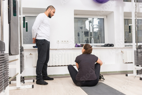 Personal trainer standing talking to a young woman