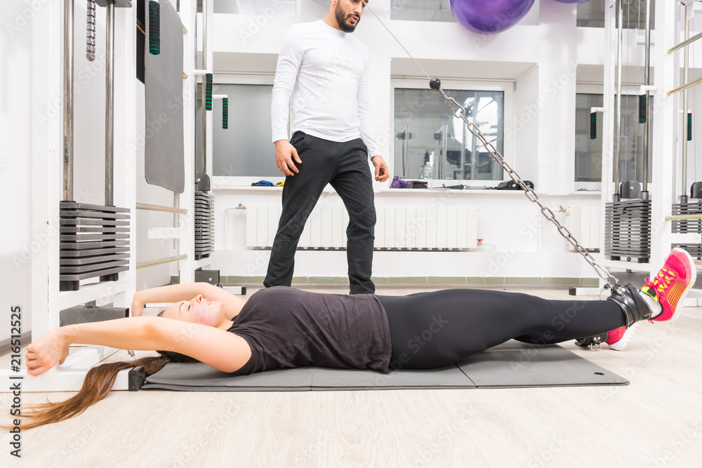 Fototapeta premium Woman exercising legs on cable machine at gym