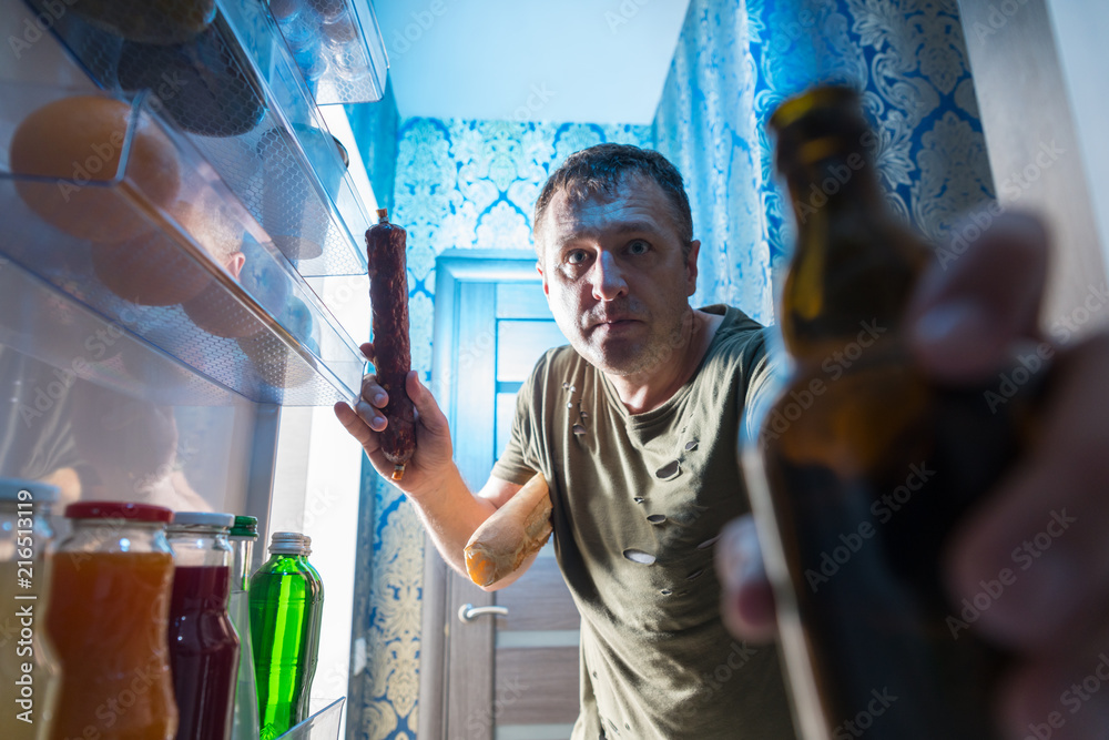 Man grabbing a salami and beer from the fridge