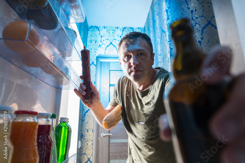 Obraz na płótnie Man grabbing a salami and beer from the fridge w salonie