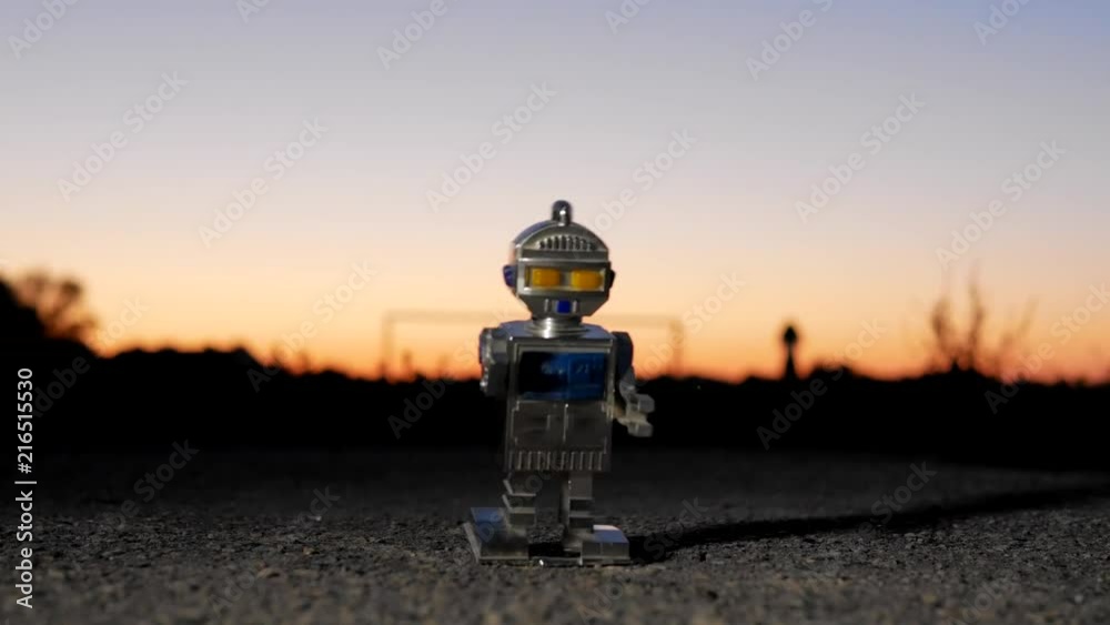 Retro mechanic robot toy travels at the evening outside the city Retro mechanic robot toy travels at the evening outside the city
