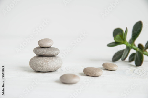 Pyramids of white zen stones with green leaves on white background. Concept of harmony  balance and meditation  spa  massage  relax