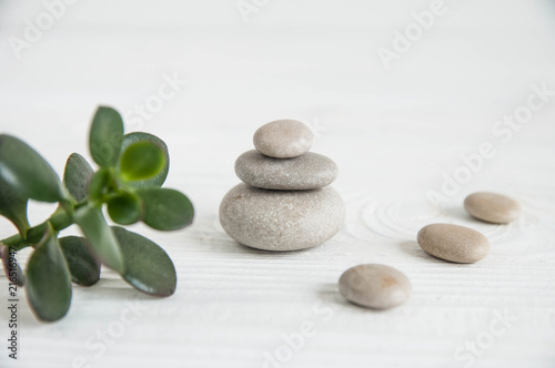 Pyramids of white zen stones with green leaves on white background. Concept of harmony, balance and meditation, spa, massage, relax